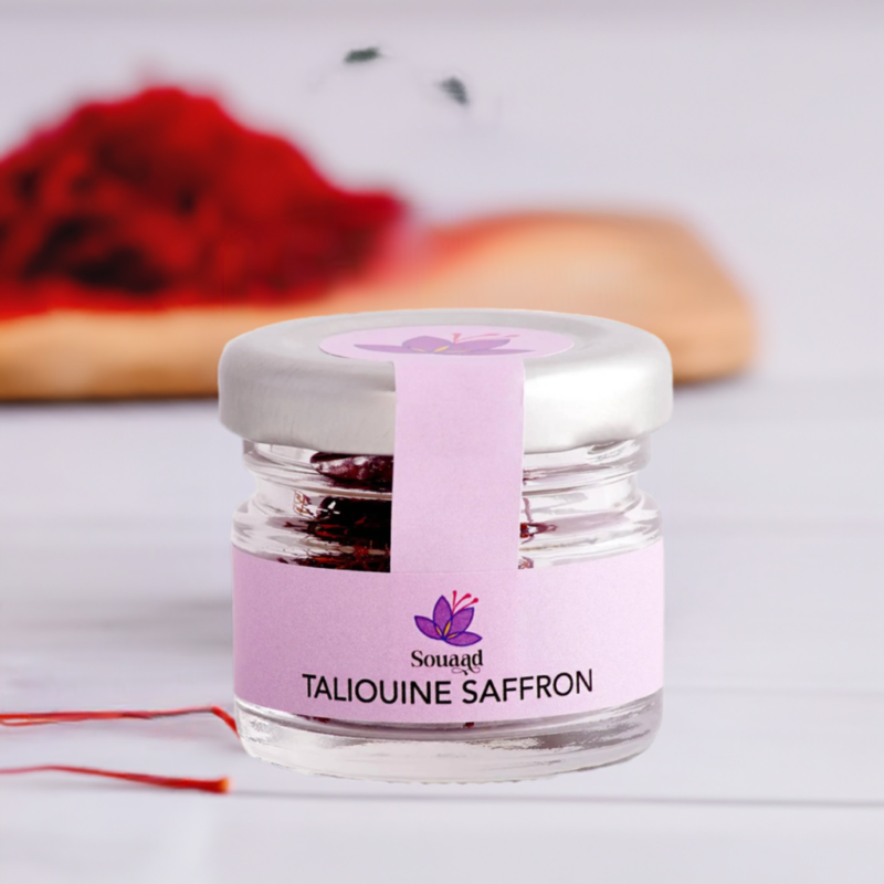 Glass jar containing 1g of Souaad's moroccan saffron set in front of saffron threads highlighting the vibrant red hues of the spice